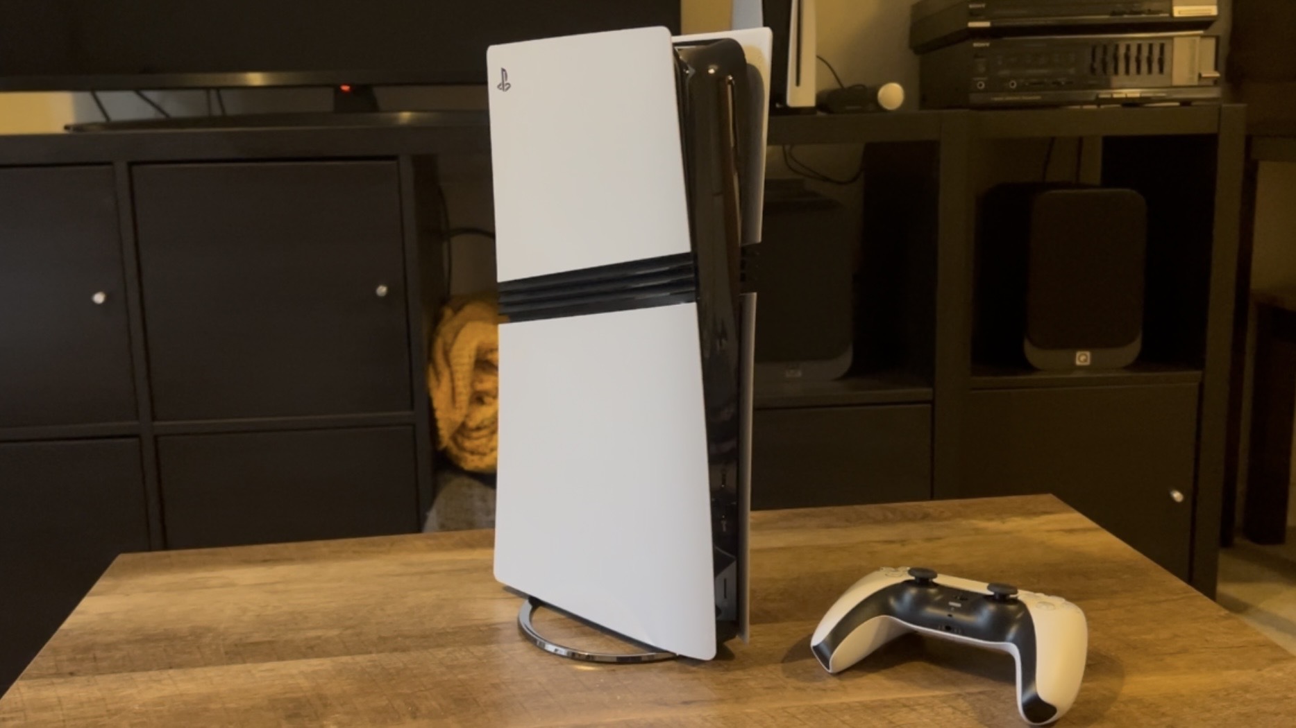 PS5 Pro console on a wooden table with DualSense controller