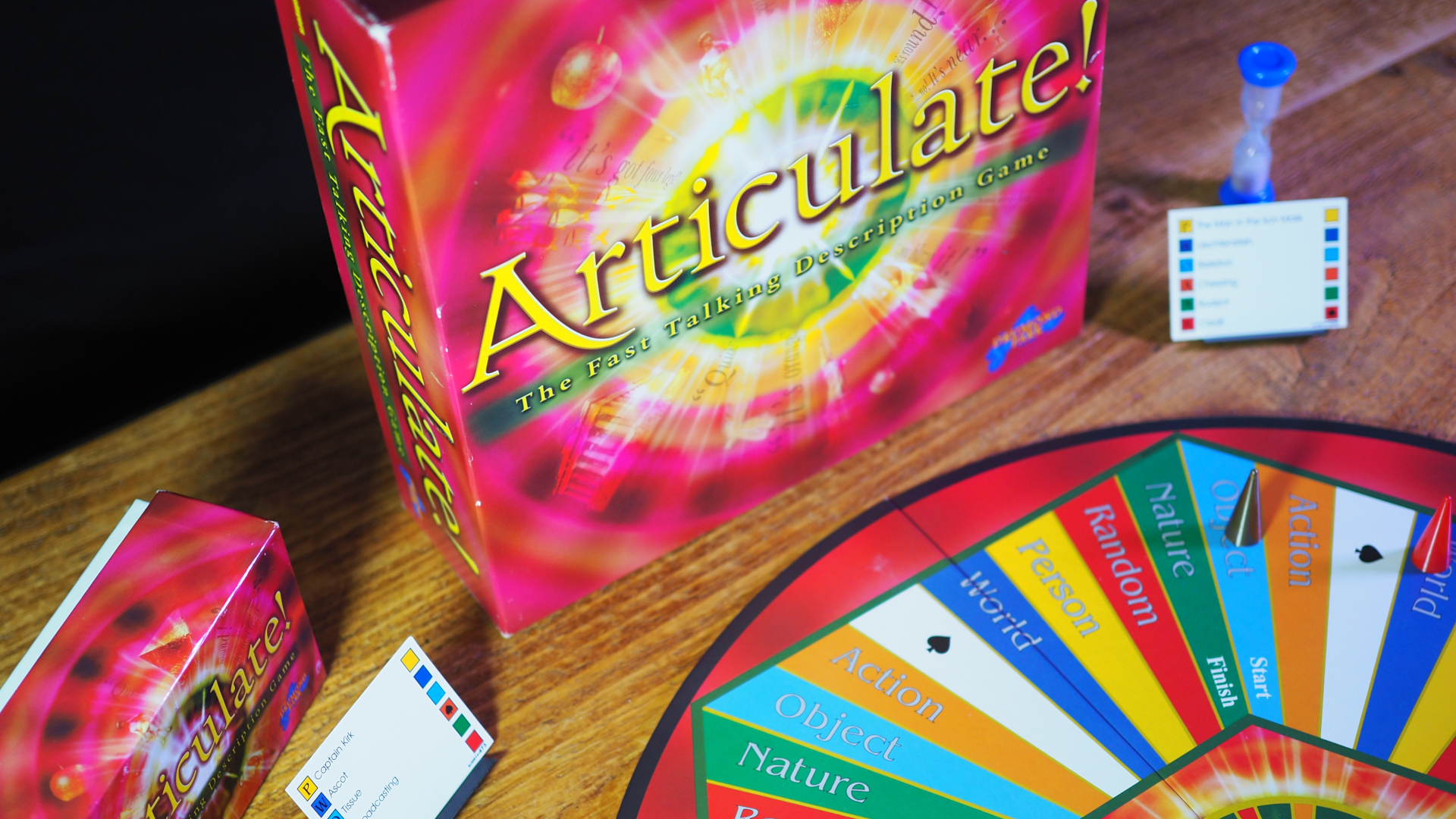 Articulate box, cards, board, and tokens on a wooden table