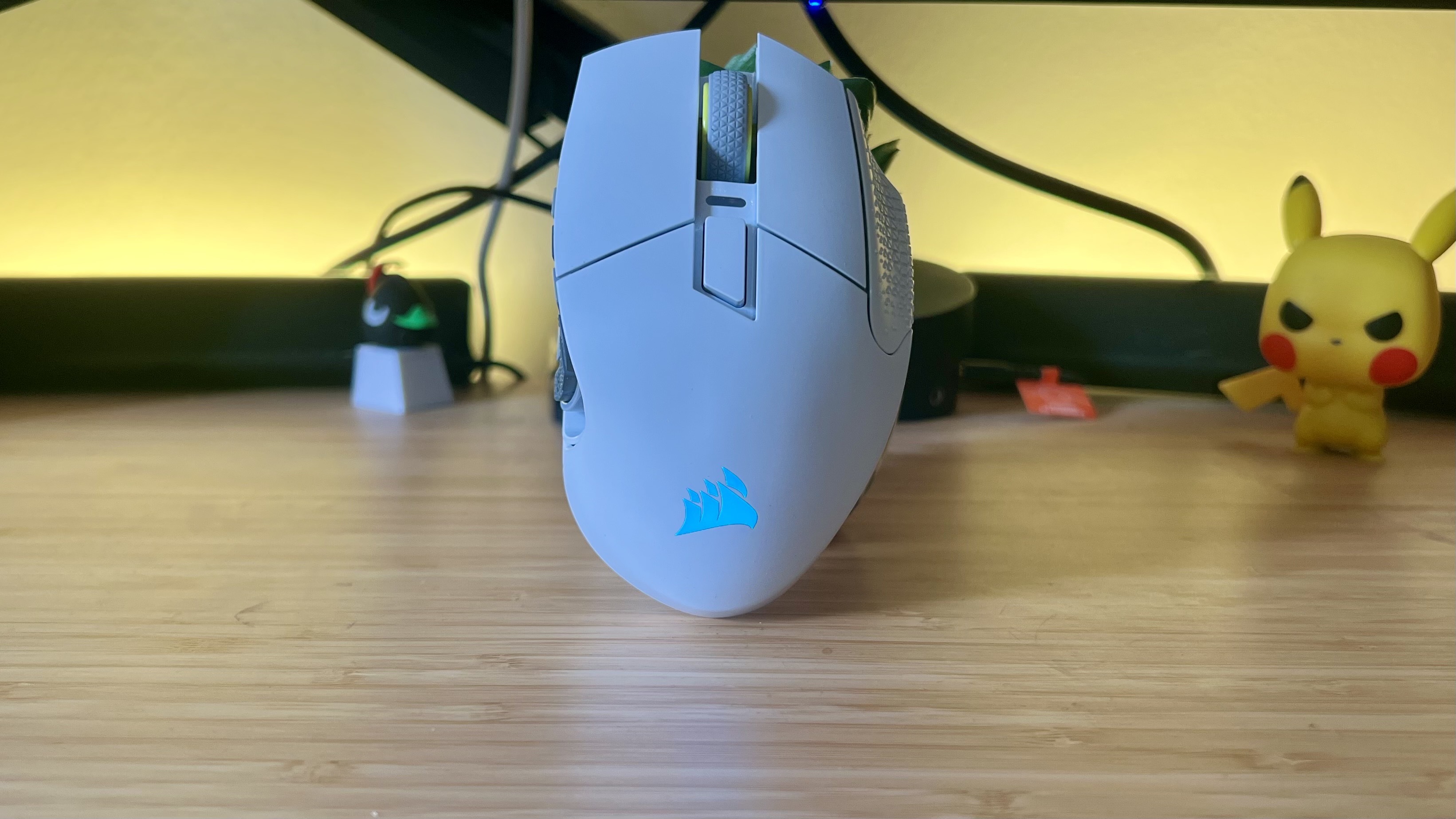 Corsair Scimitar Elite Wireless SE gaming mouse on a wooden desk with yellow backlighting