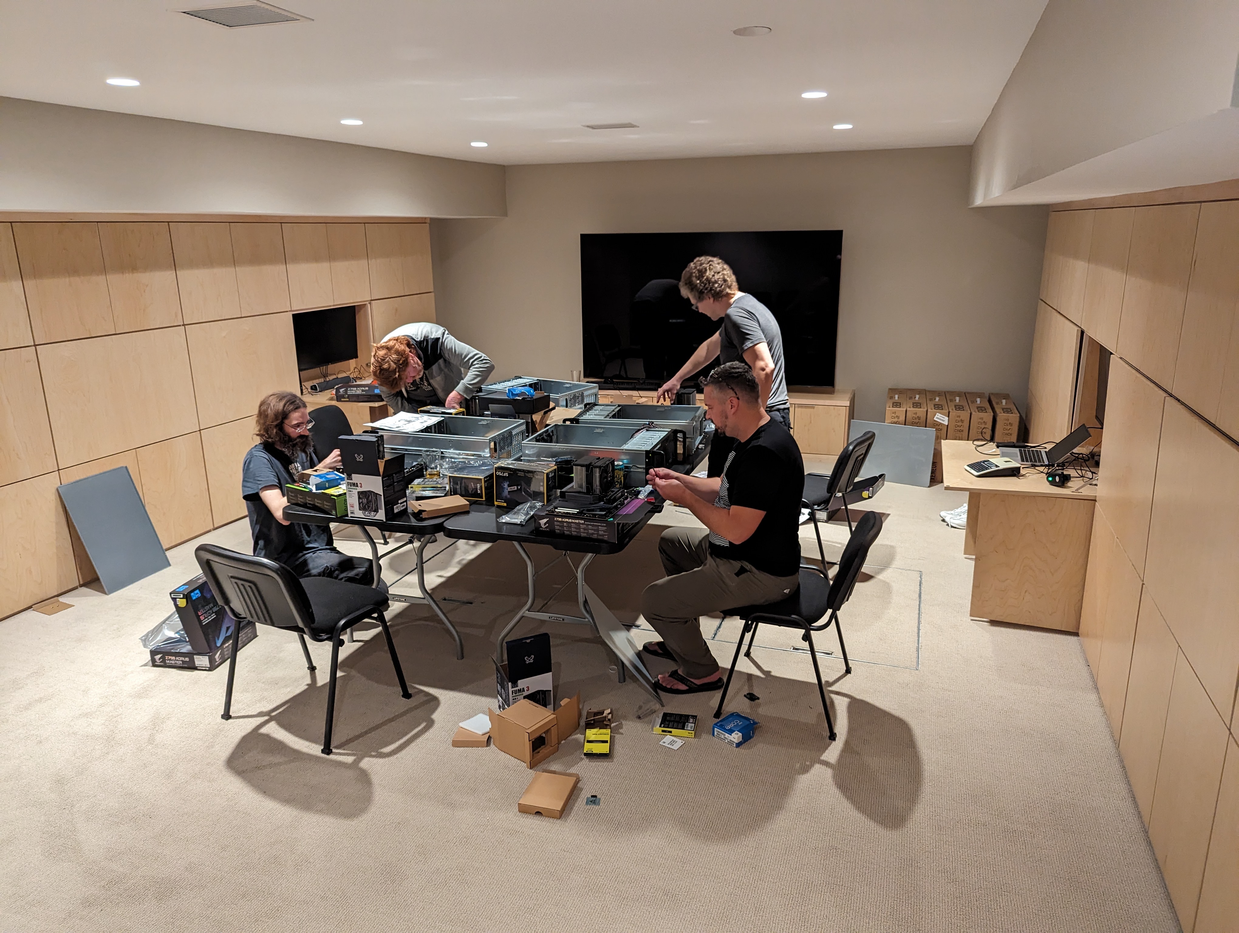 eklhqu23nokkzsuehrnqvd A number of people sit around a table, assembling PC hardware.