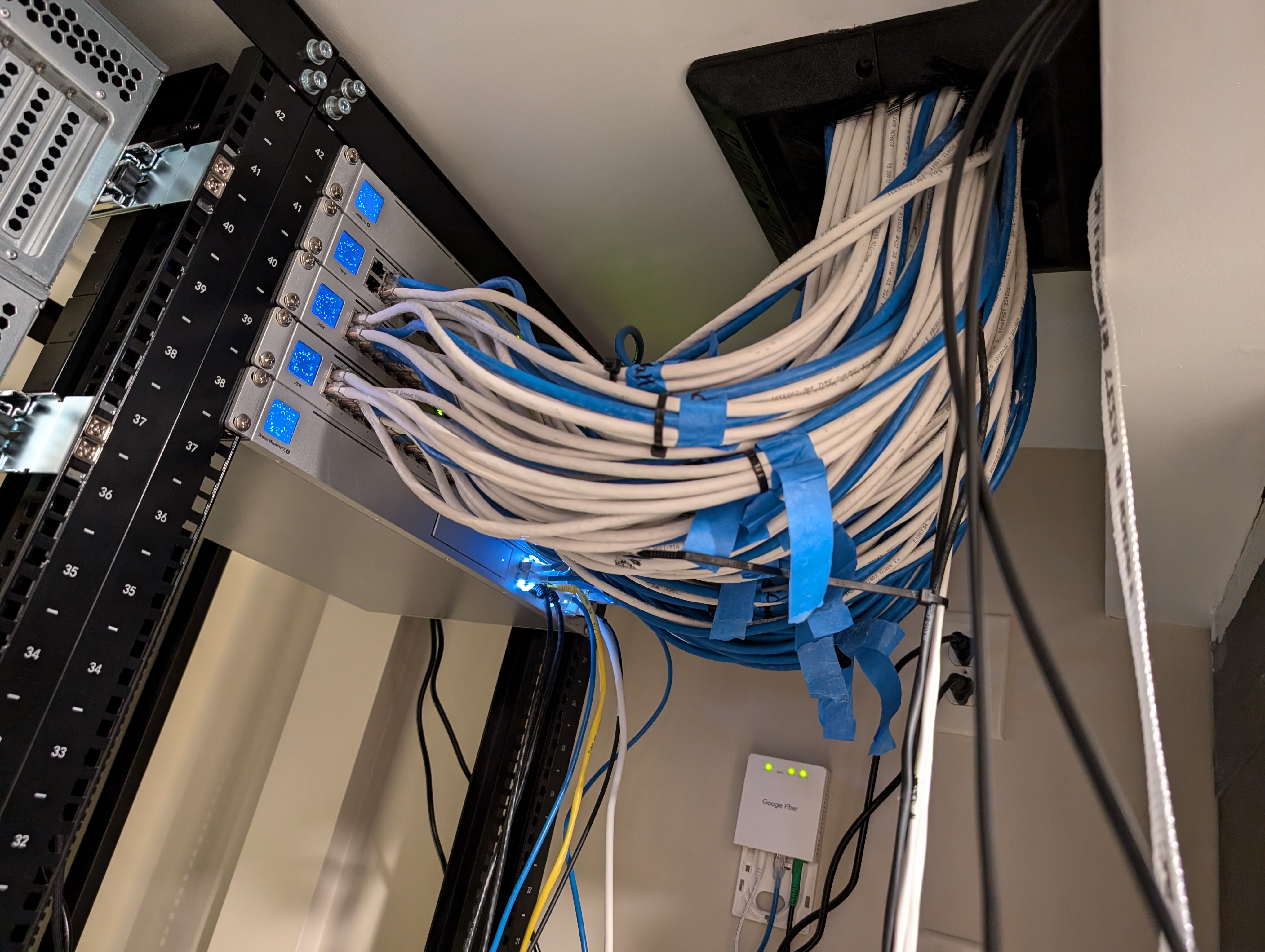 tpqskdths7eaazr99z9g9f A mass of blue and white cables snakes between two parts of the LAN party house.